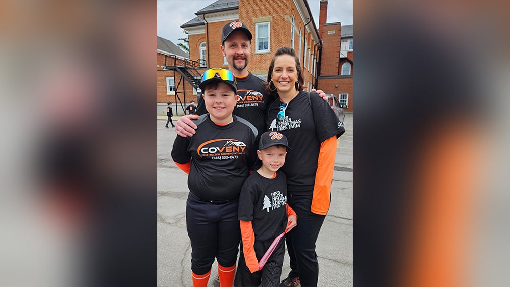 Man woman two young boys smiling at camera in black and orange baseball gear