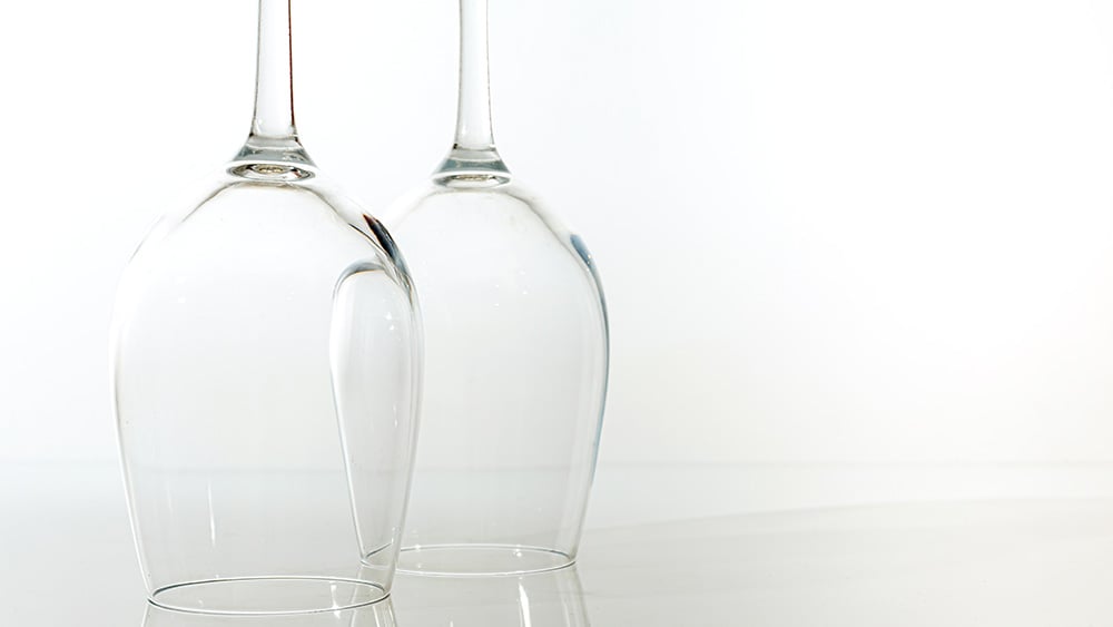 Two inverted glasses for wine with reflection on a white background
