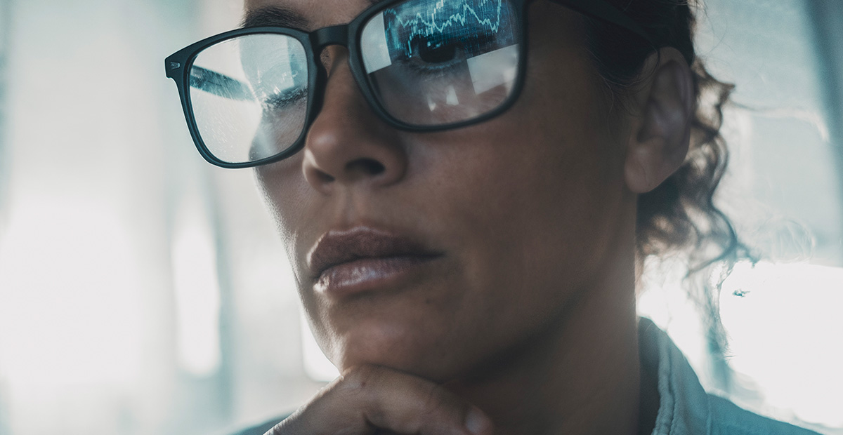 Technology concept people portrait with digital charts reflected on eyewear. One woman in business online modern activity looking a display with reflection on glasses. Concept of businesswoman alone