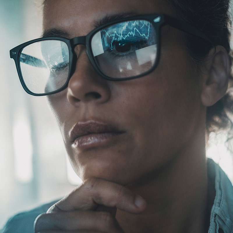 Technology concept people portrait with digital charts reflected on eyewear. One woman in business online modern activity looking a display with reflection on glasses. Concept of businesswoman alone