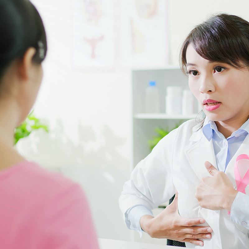 An Asian female doctor consults with a female patient about breast surgery in an office setting