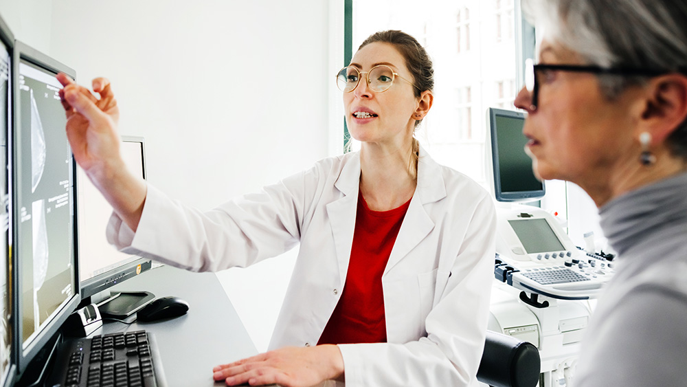 Female physician points at screen with older white female patient
