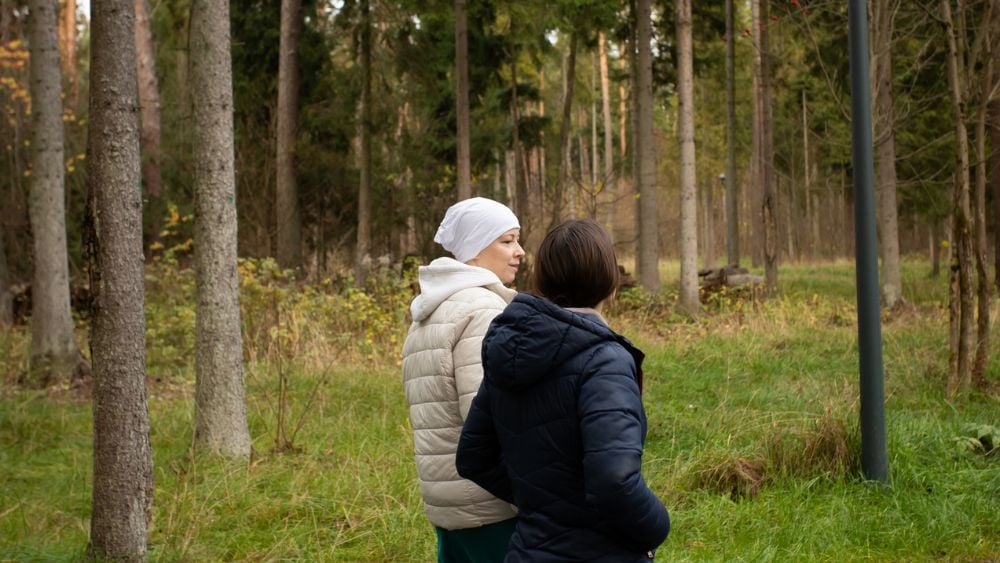 Cancer patient and friend walking through woods during autumn
