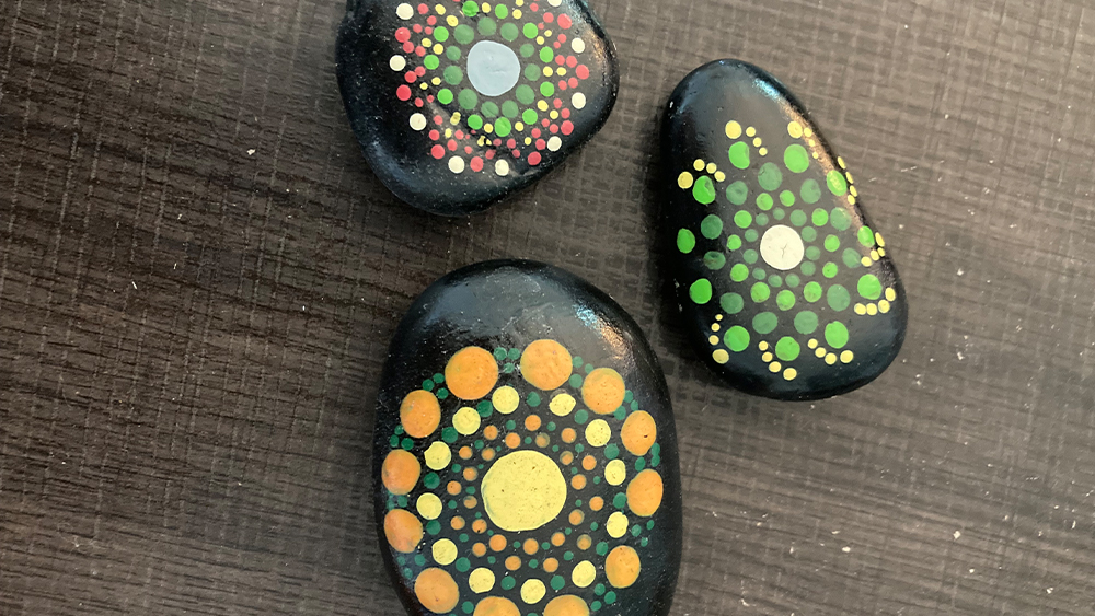 three hand painted rocks with artistic designs