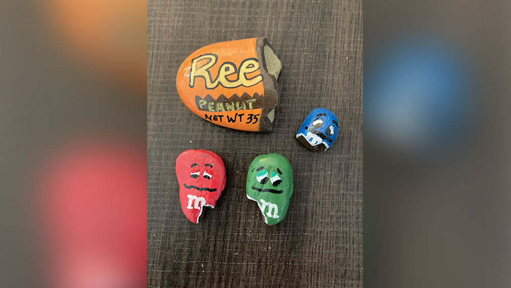 four hand painted rocks featuring a reese's peanut butter cup broken in half and three M&Ms