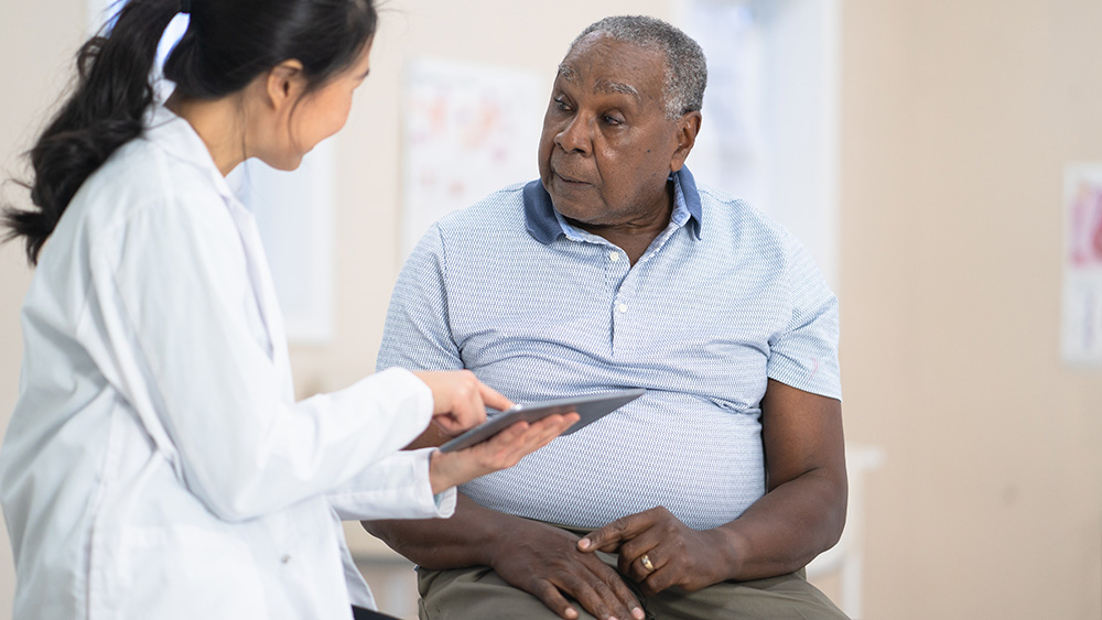 Female Asian physician talks with older African American man