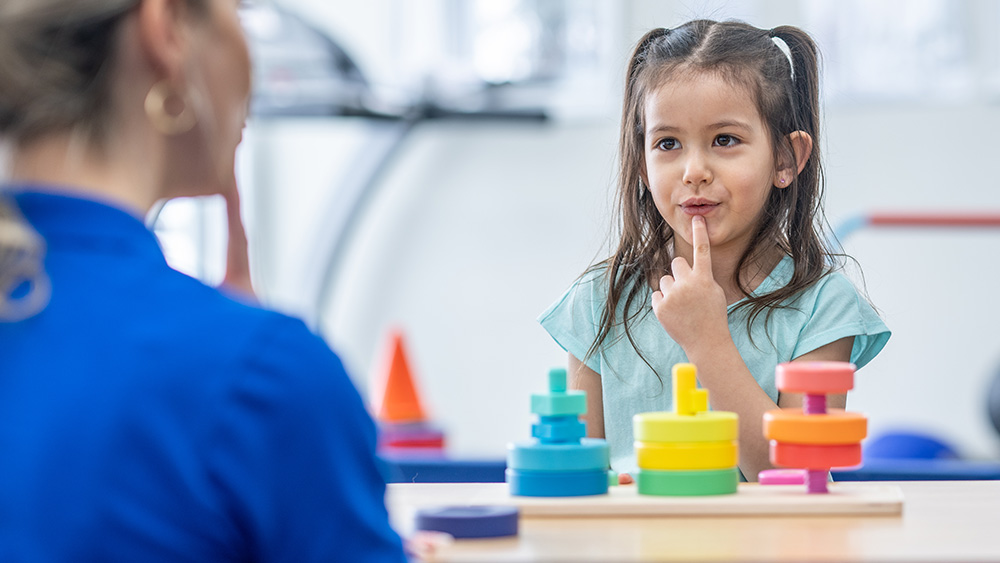 Female speech therapist working with young girl