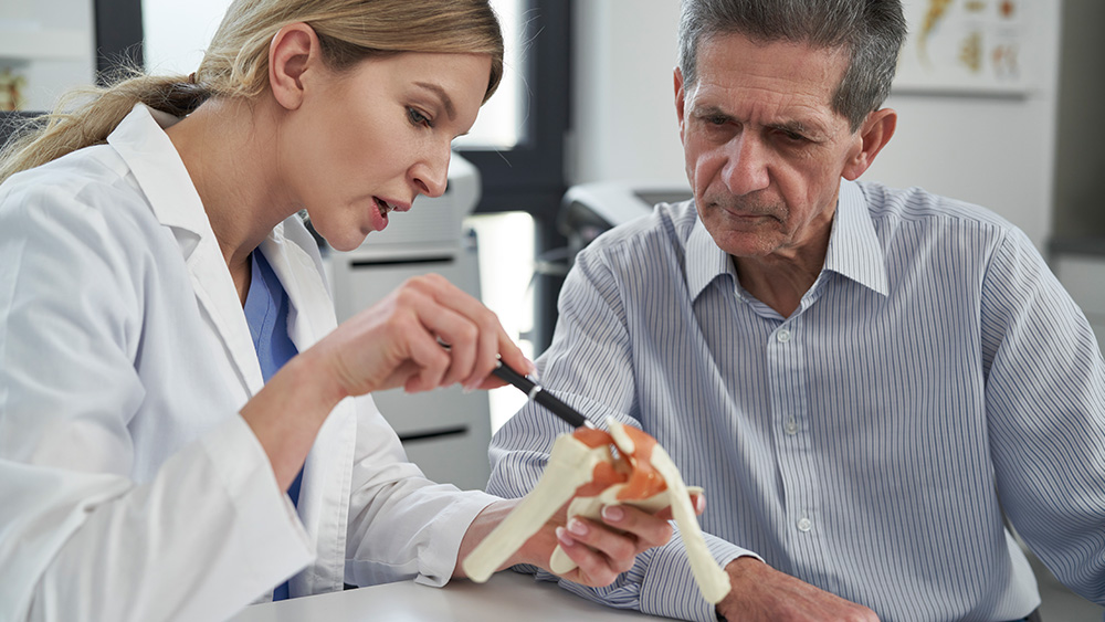 Female doctor explaining joint replacement to older male patient