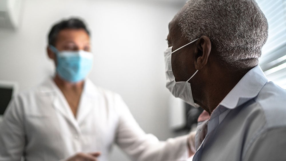 Doctor giving emotional support to a senior patient using face mask
