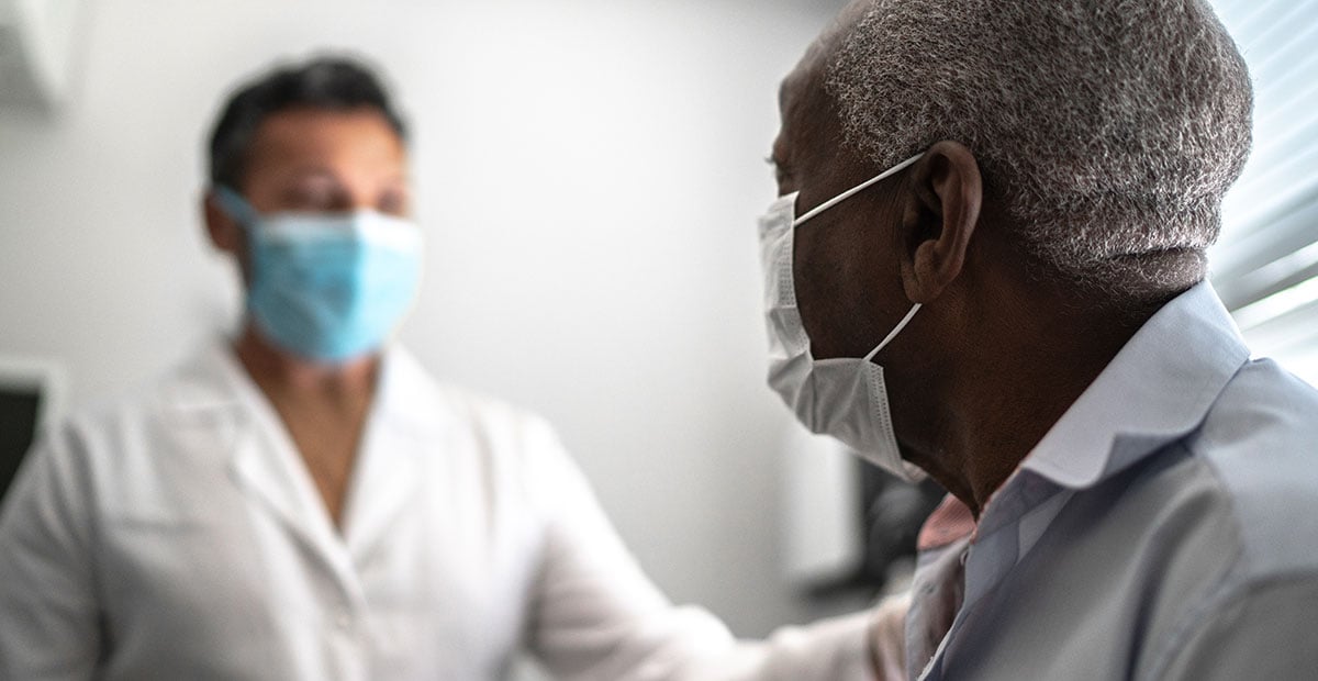 Doctor giving emotional support to a senior patient using face mask