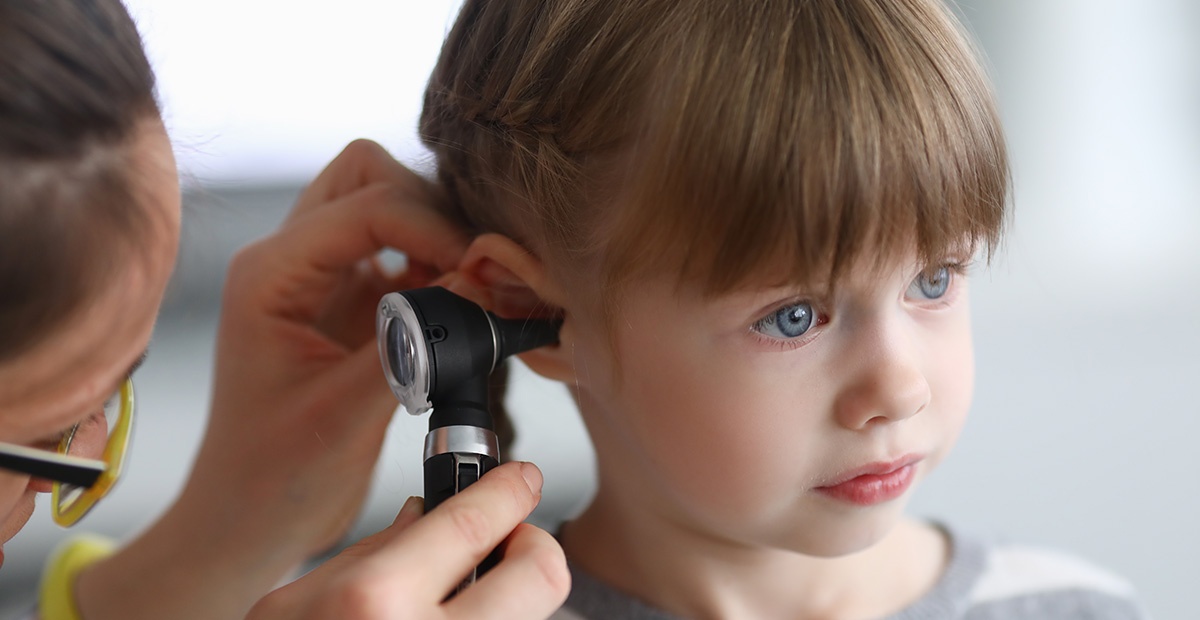 Otorhinolaryngologist examines little girl's ear with otoscope