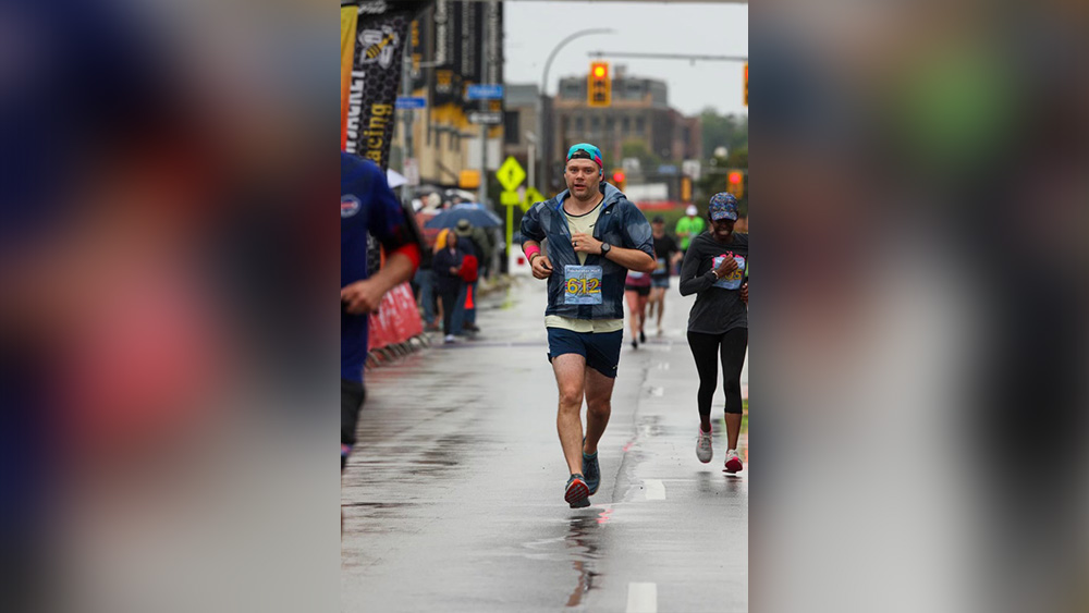 Man running across finish line on rainy day