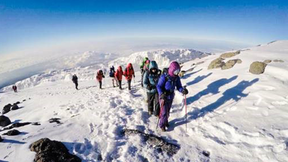 Group of people in winter gear climbing up snowy mountain