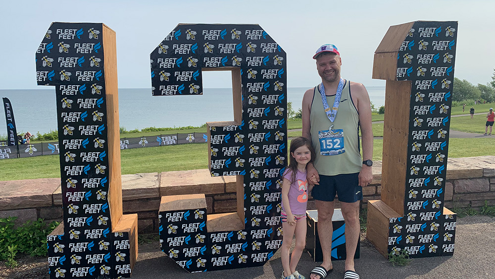 White man young girl in summer weather standing in front of 13.1 sign