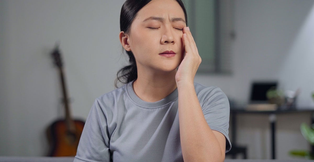 Asian woman was sick with eyes pain, irritate itching her eyes, sitting on sofa in living room at home