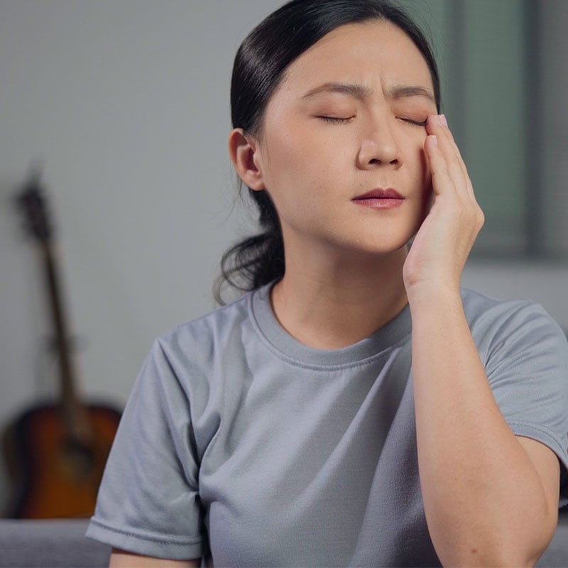 Asian woman was sick with eyes pain, irritate itching her eyes, sitting on sofa in living room at home