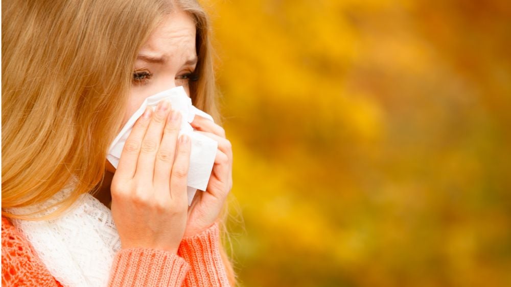 Women outside blowing nose during fall season