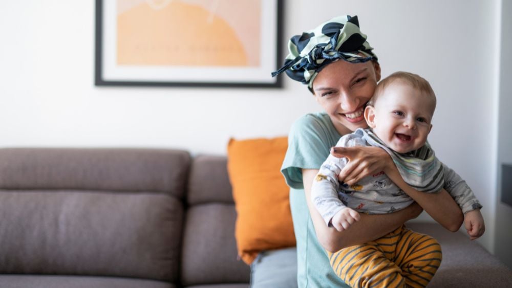 Young mother with cancer holding infant