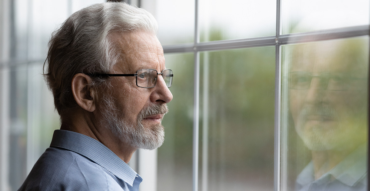Pensive elderly mature senior man in eyeglasses looking in distance out of window, thinking of personal problems. Lost in thoughts elderly middle aged grandfather suffering from loneliness