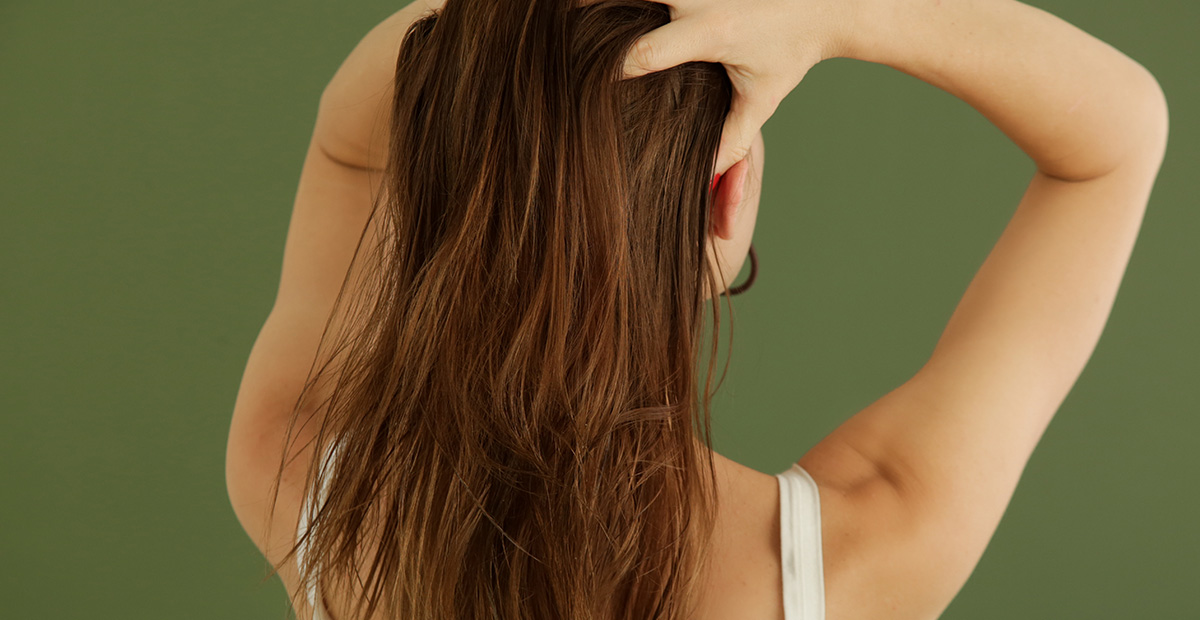 Studio shot of woman applying hair oil with her fingers