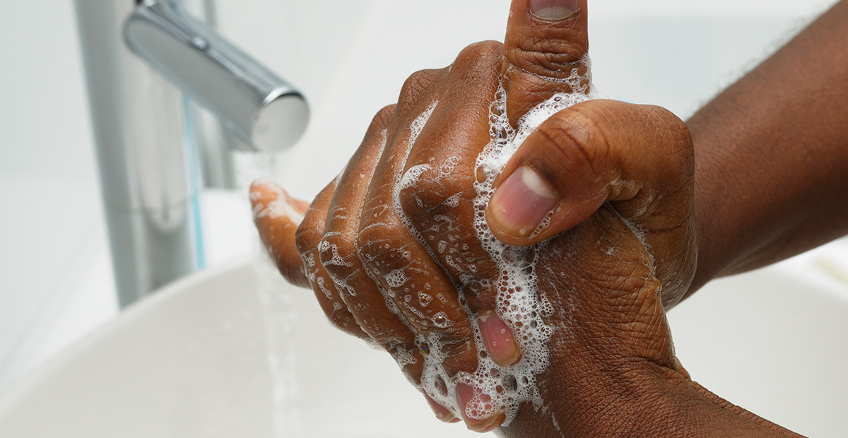 Black person washing their hands with soap and water