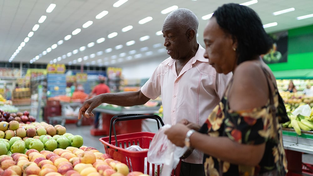 Older Black couple looks at produce in supermarket