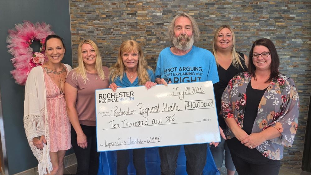 Howie Zwelling and Lipson Cancer Institute staff holding a novelty fundraiser check