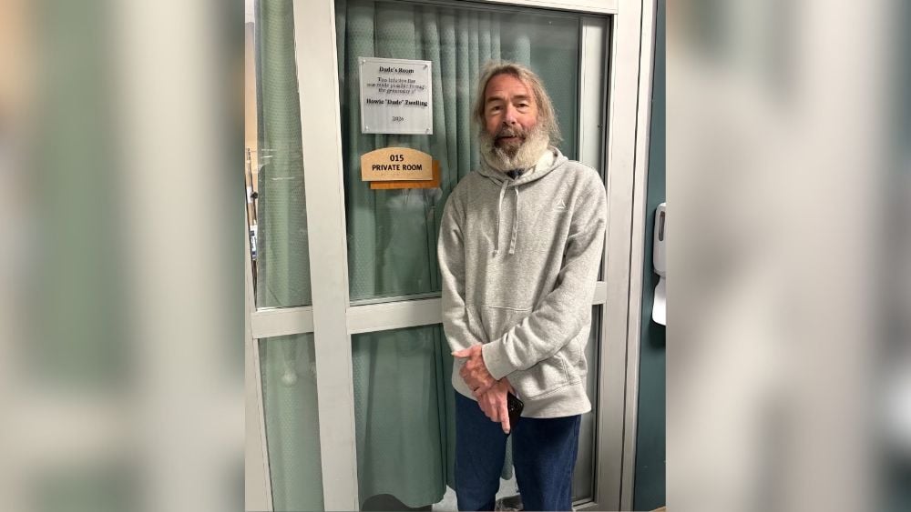Howie Zwelling standing next to infusion room named for him