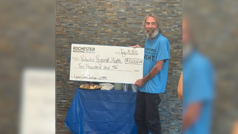 Howie Zwelling holding a novelty check made out to Lipson Cancer Institute