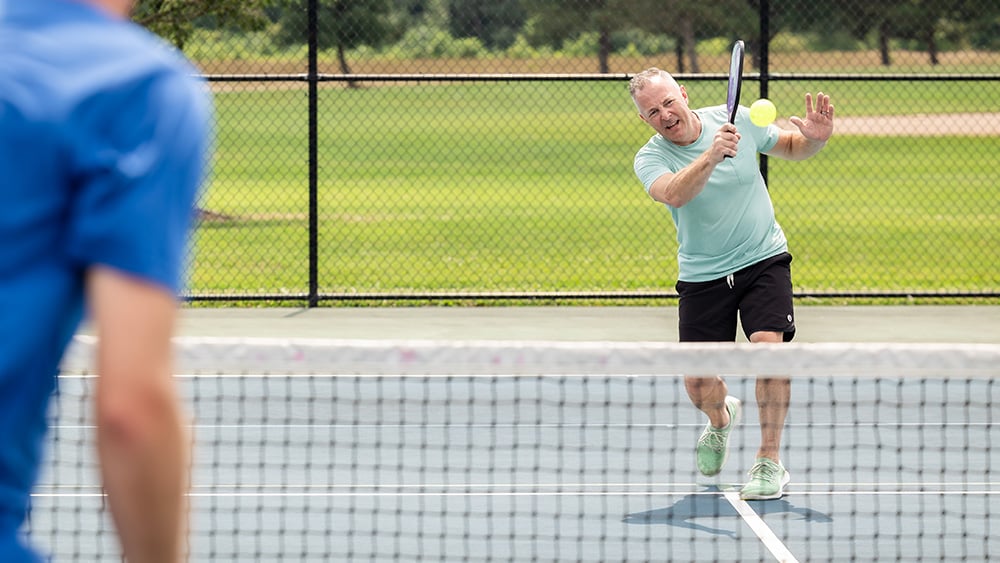 Middle aged man plays pickleball