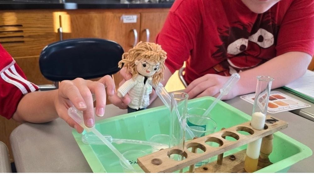 A crocheted miniature version of Janis Becker as a science teacher