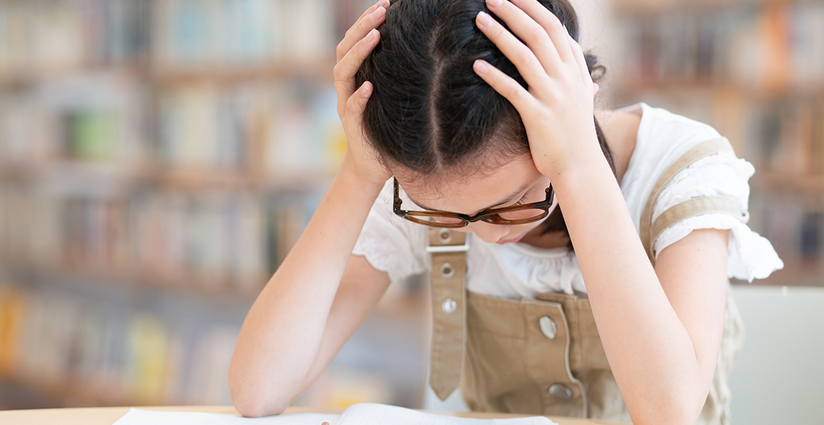 girl holding her head while studying