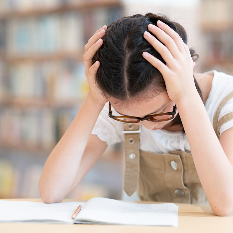 girl holding her head while studying