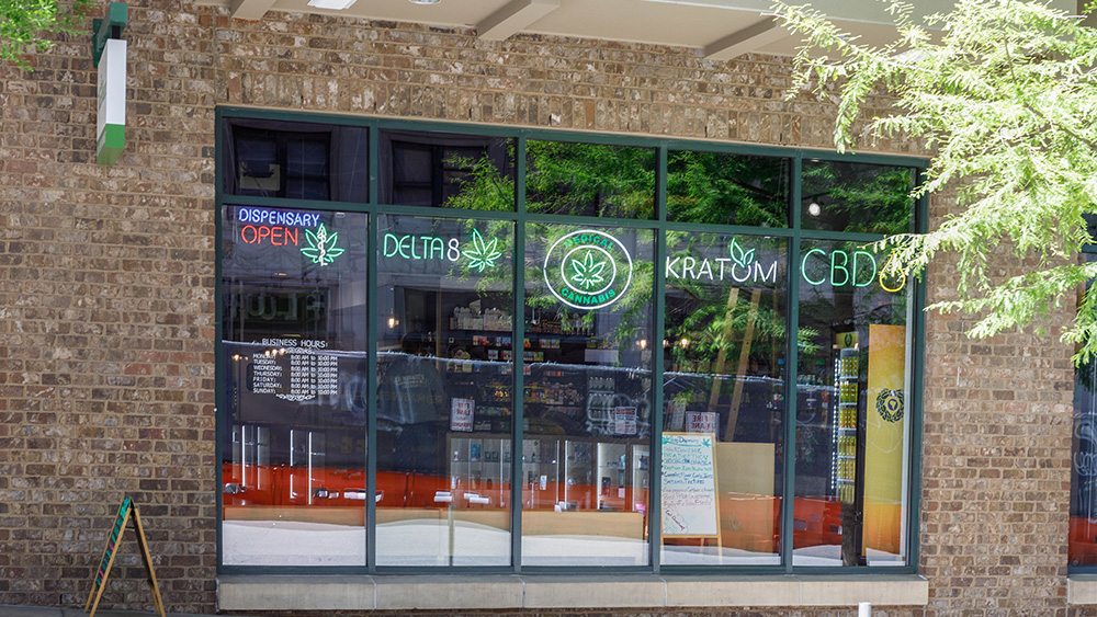 Storefront with neon cannabis and kratom signs in the window