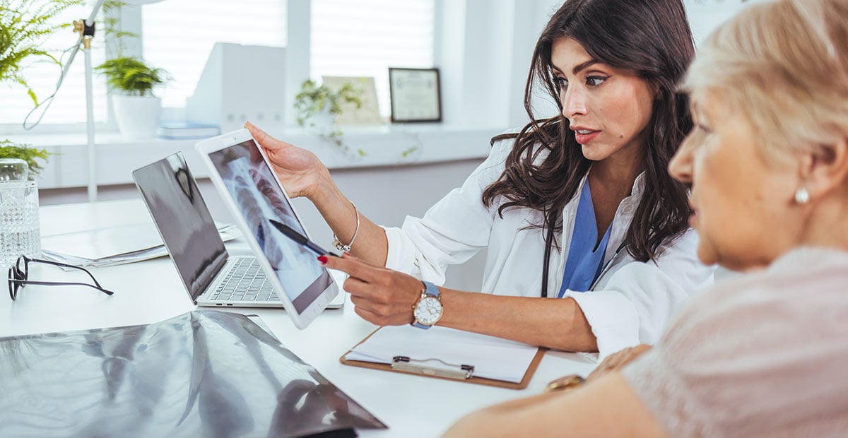 Lung cancer concept. Doctor explaining results of lung check up from x-ray scan chest on digital tablet screen to patient. The doctor is analyzing and clarifying images of the patient's lung X-rays.