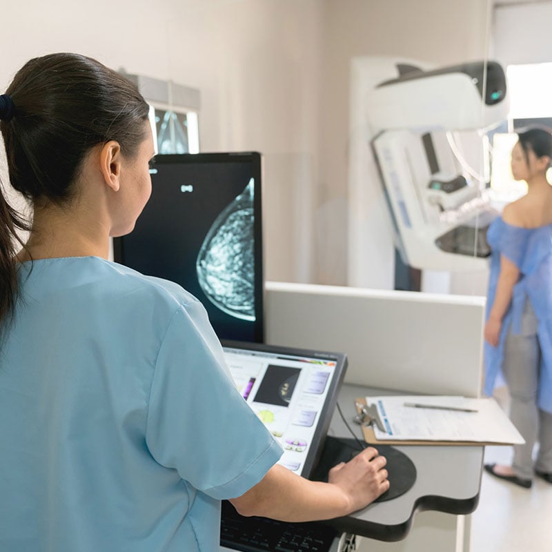 Unrecognizable nurse taking a mammogram exam to an adult patient at the hospital