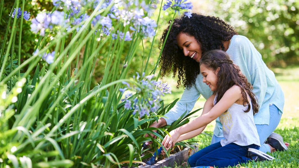 Woman and young child in flower bed outside