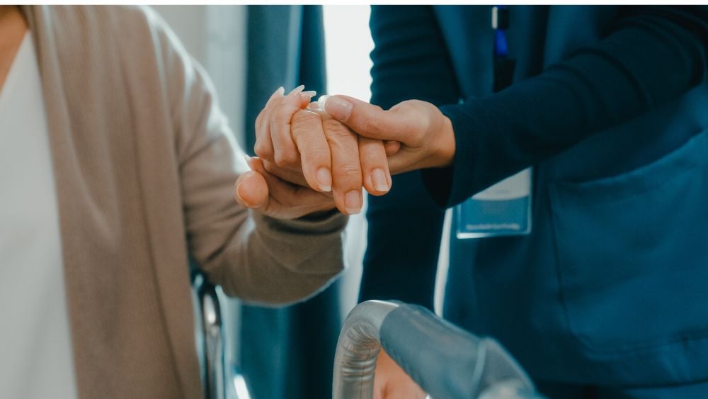 Healthcare provider holding hand of dying patient