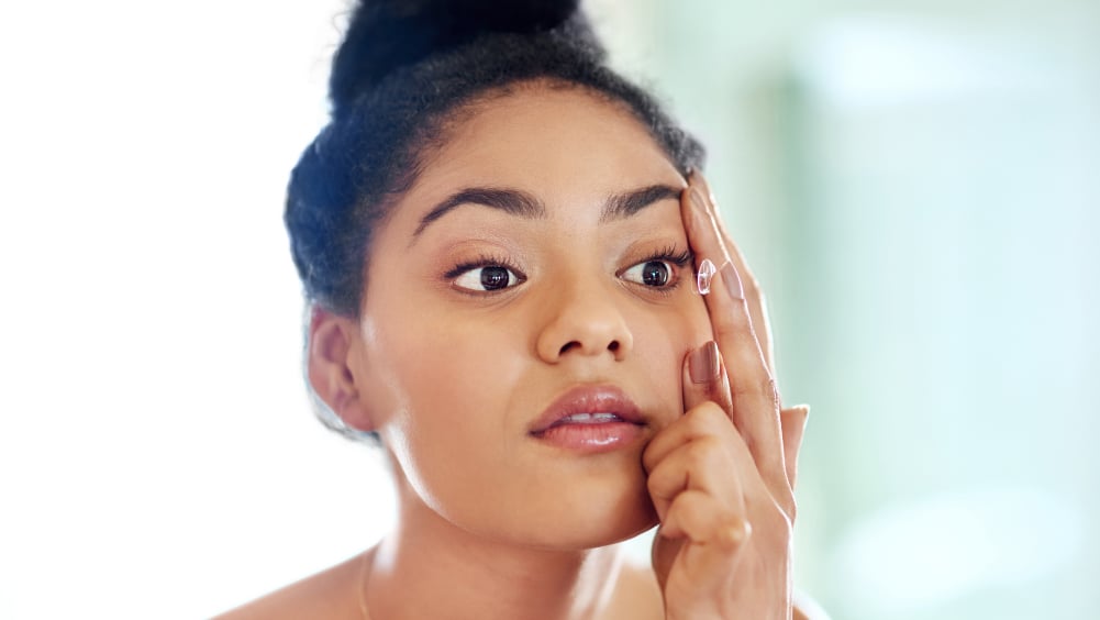 Young Black woman putting contact lenses in