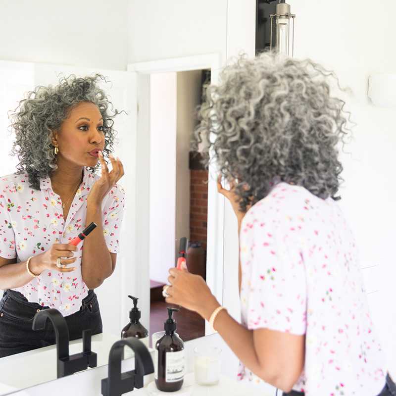 A beautiful black woman puts on her makeup in a bathroom
