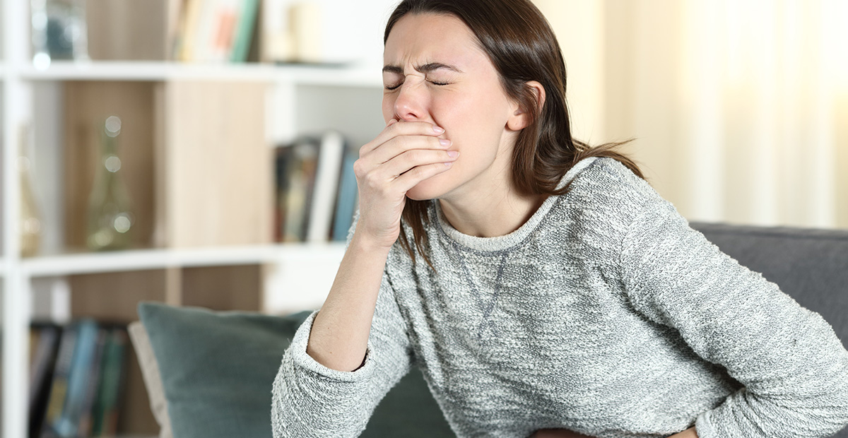 Stressed woman with a stomach ache about to vomit on a couch at home
