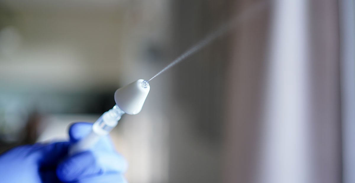 Hand holding a syringe with a mucosal atomization decive (MAD) used for intranasal application of drugs