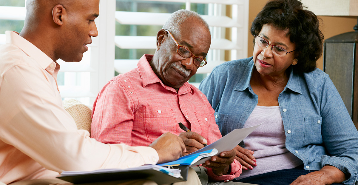 Black man and woman discuss paperwork with older Black man