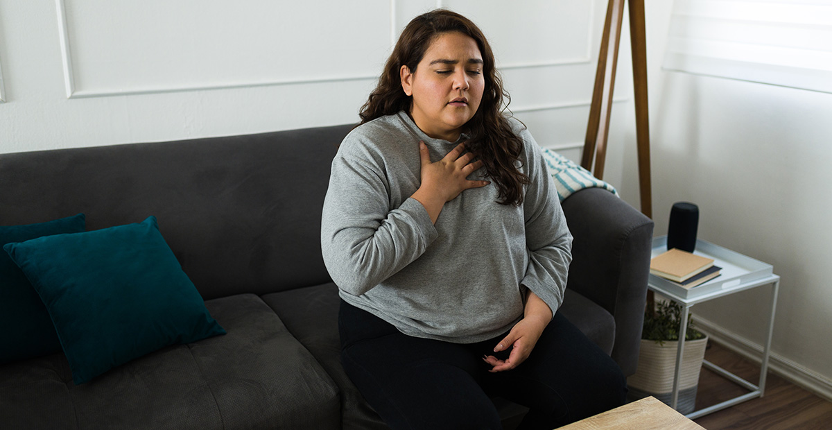 Stressed hispanic woman suffering from hyperventilation or an anxiety attack while feeling stressed at home