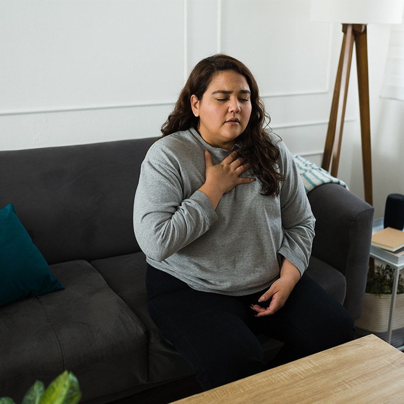 Stressed hispanic woman suffering from hyperventilation or an anxiety attack while feeling stressed at home