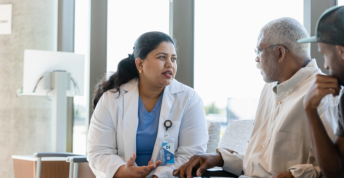 The compassionate mid adult female doctor discusses sensitive medical issues with her senior adult male patient as the young adult son listens in.