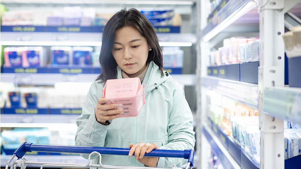Woman looking at sanitary pads in grocery store