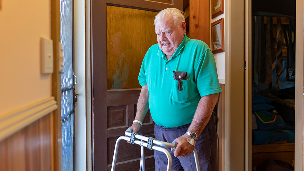 Senior Man With a Walking Frame Answering the Door at Home