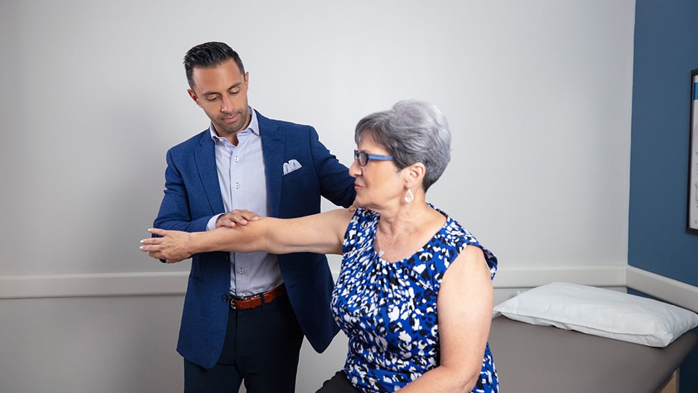 male doctor holding female patient's arm and examining her shoulder