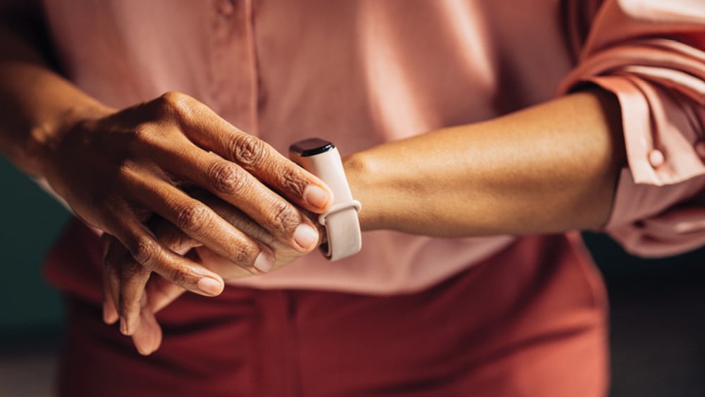 African American woman checking heart rate on FitBit on wrist